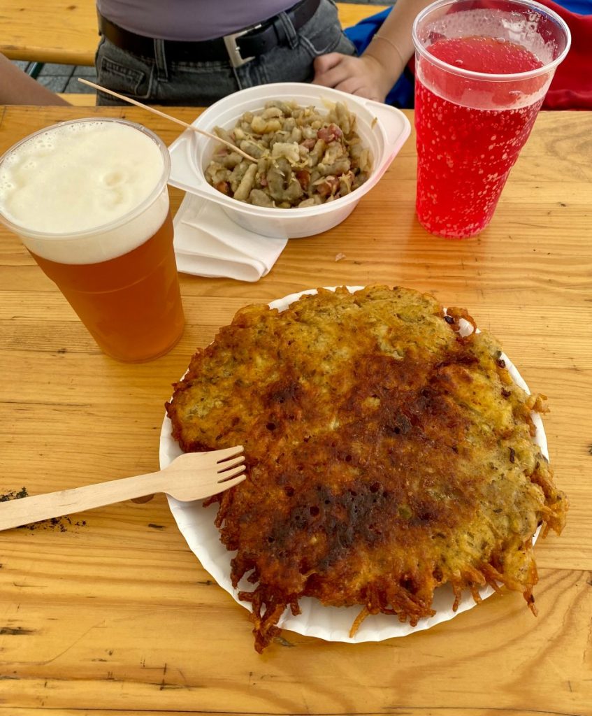A plate of fried potato pancake and a glass of beer on a table in Brno.