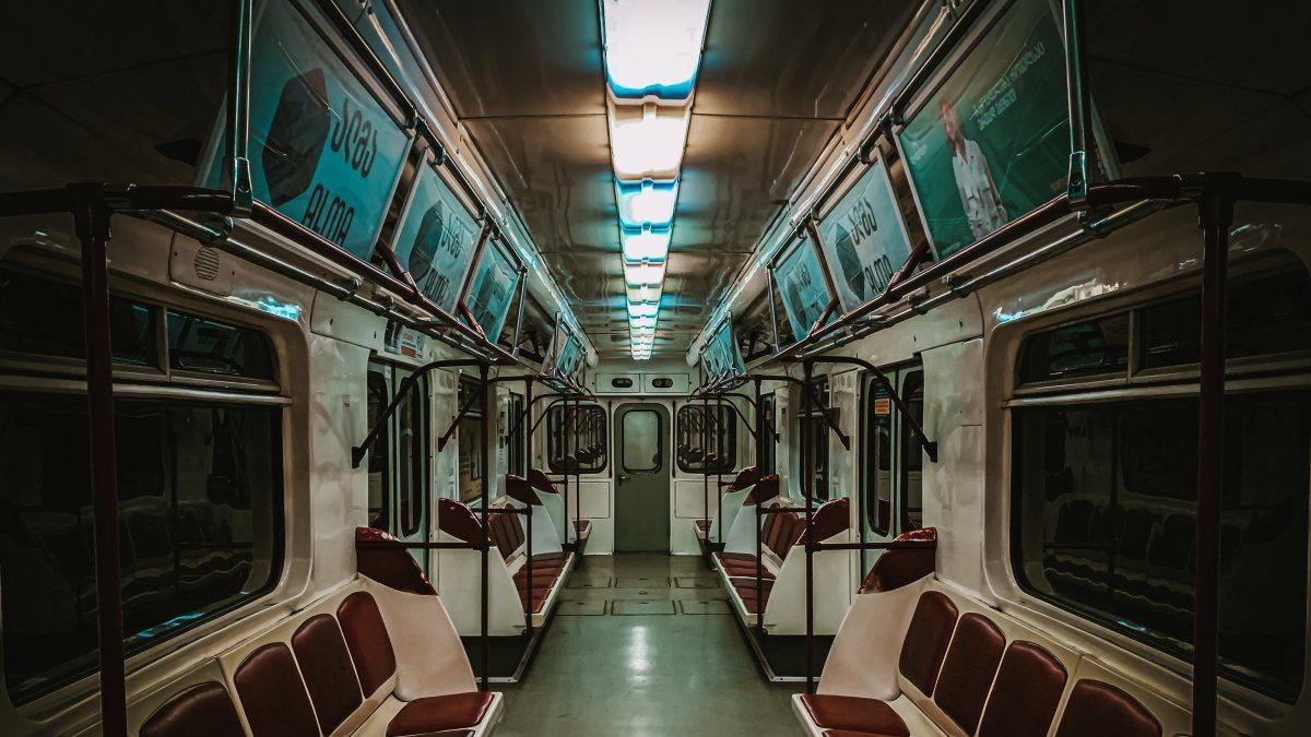 An empty subway car with red and white seats.
