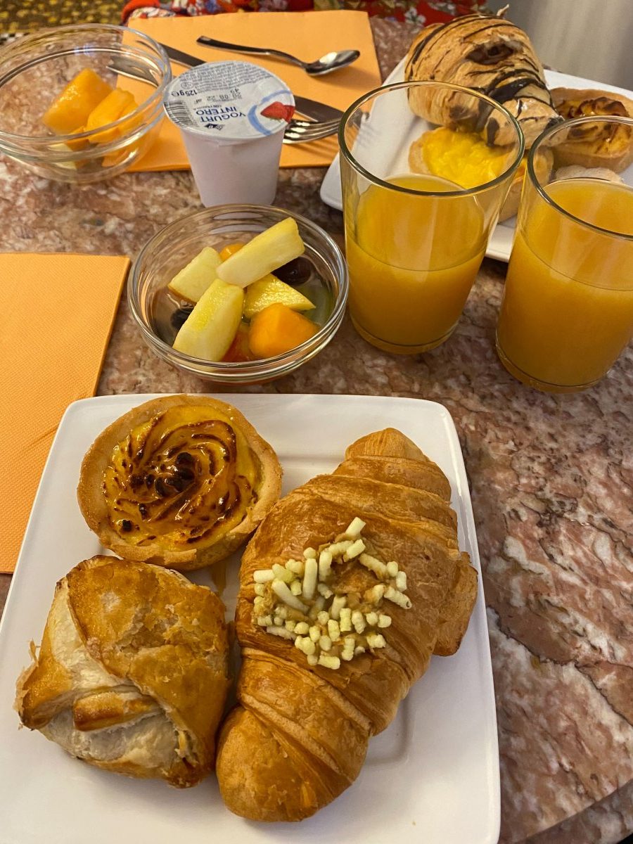 A plate with croissants and orange juice on it, part of the Locandra art deco breakfast.
