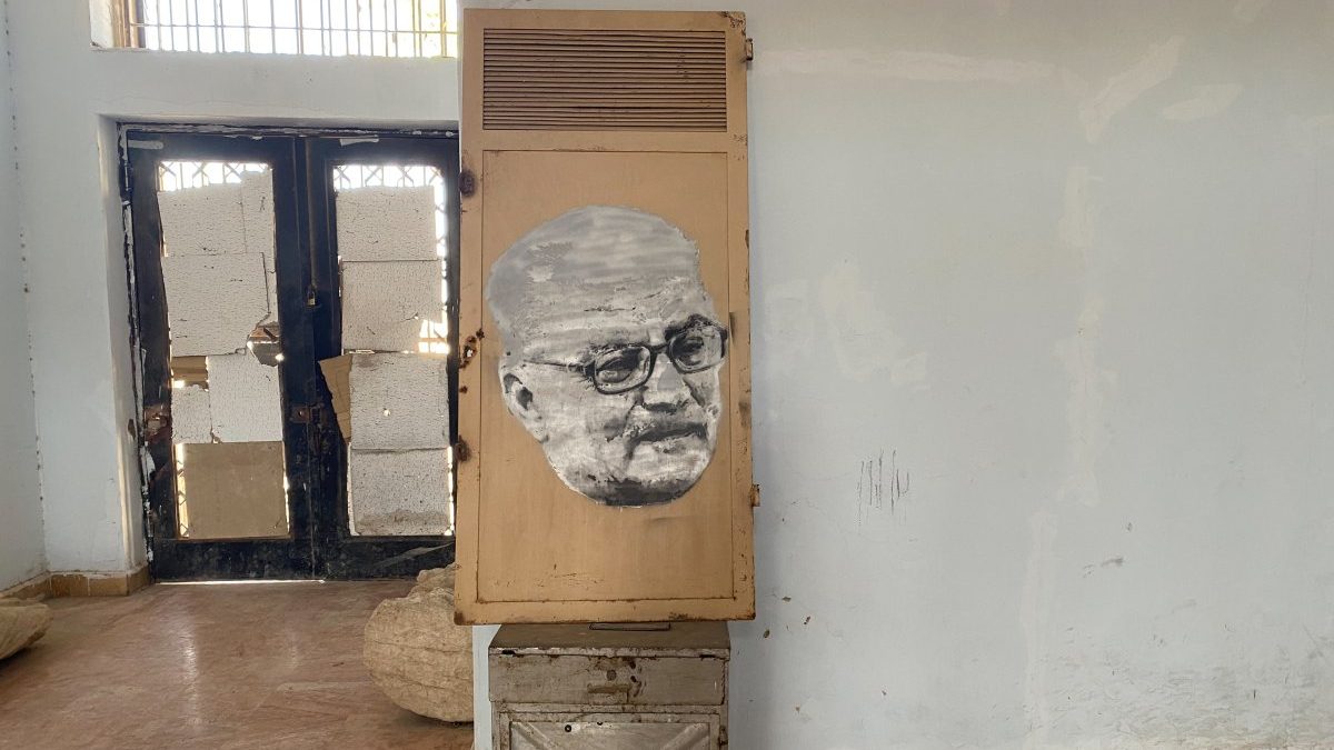 A decaying door showcasing a worn picture of the former manager of the palmyra Museum, who gave his life to save the ancient artifacts