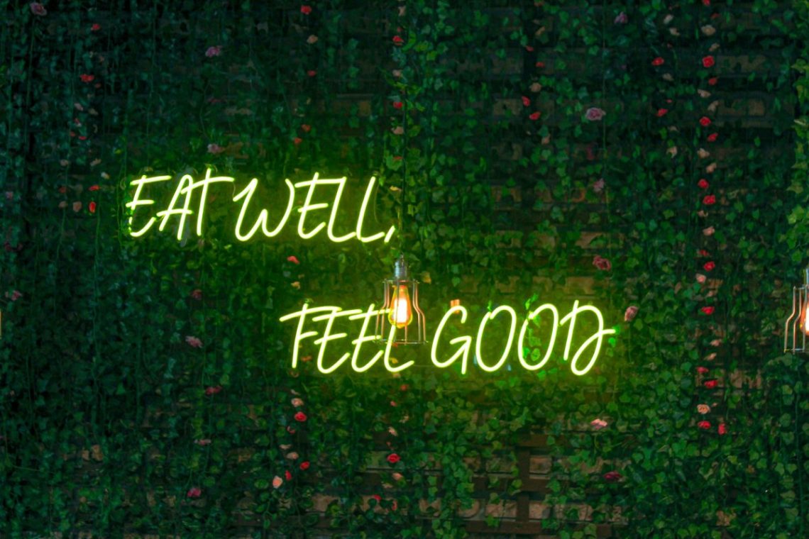 A neon sign saying "Eat well, feel good" perfectly showing the benefits of a plant based diet