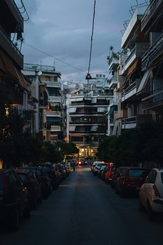 This image depicts a street lined with modern apartment buildings in Athens, highlighting the vibrant urban atmosphere and convenient location for first-time visitors.