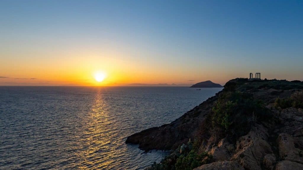 Sunset over the Aegean sea from Cape Sounion with rocky cliffs.