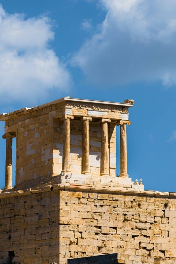 The image features the temple of Athena Nike with classical columns, set against a bright blue sky, highlighting historical architecture.