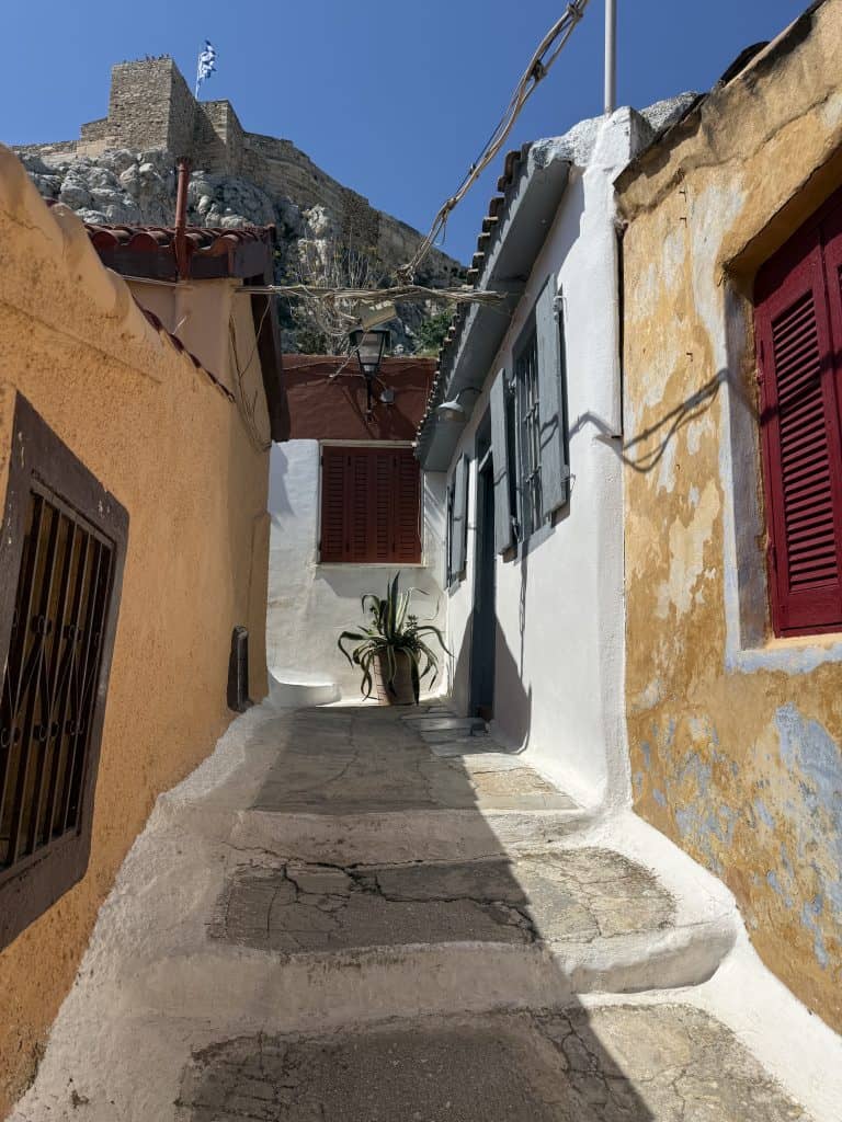 A narrow path in the Anafiotika neighbourhood. The street is whitewashed, while the one-story buildings on each side are orange.