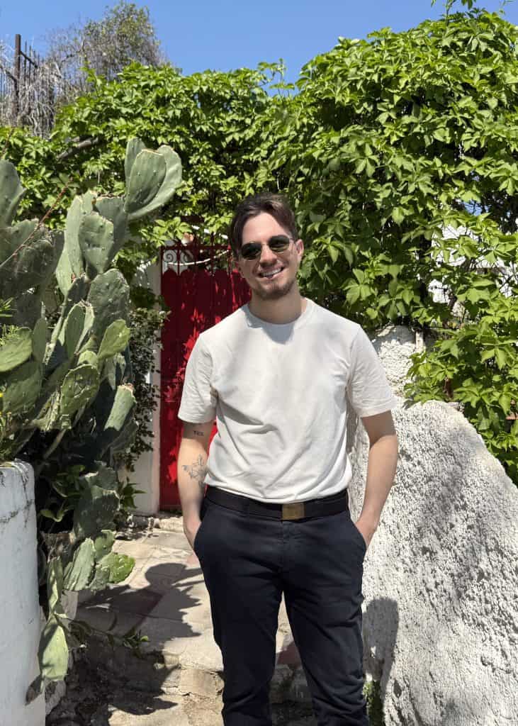 A photo of Nick in front of a beautiful red door covered with plants in the Athenian neighbourhood in Anafiotika