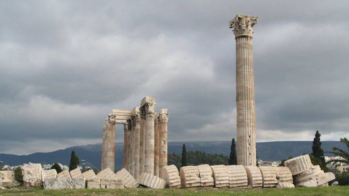 Ancient Greek ruins at the Olympion featuring tall, weathered columns under a cloudy sky.